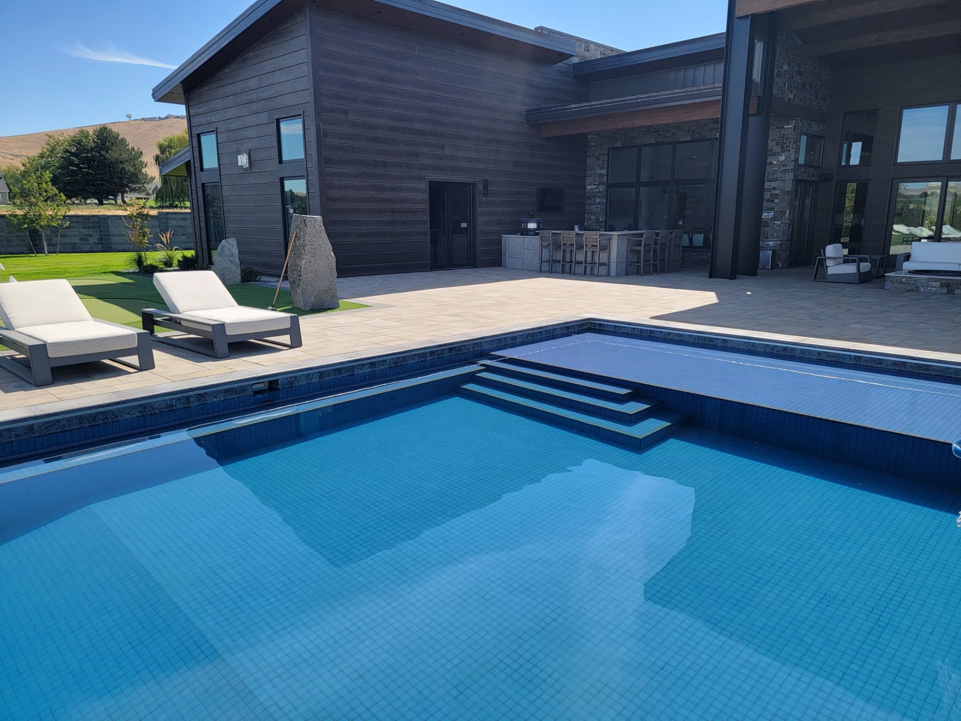 All-tile pool with integrated automatic cover and wide tiled entry steps at a contemporary Washington residence
